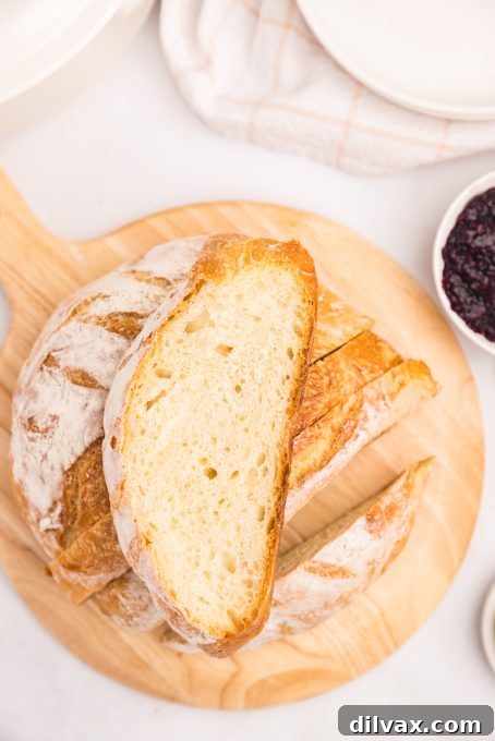 A perfectly golden-brown, freshly baked loaf of bread in a Dutch oven, ready to be removed.
