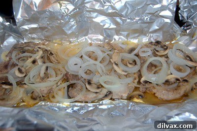 Cooked pork chops, onions, and mushrooms unwrapped from the foil packet.