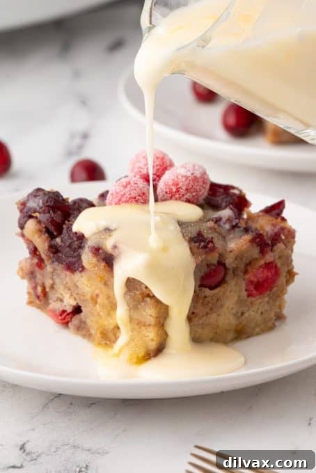 Pouring an orange Glaze over a warm Cranberry Orange Bread Pudding.