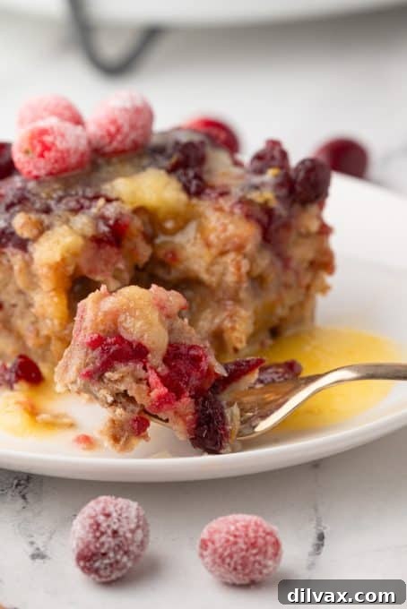 A spoonful of Cranberry Orange Bread Pudding, showing cranberries and walnuts.