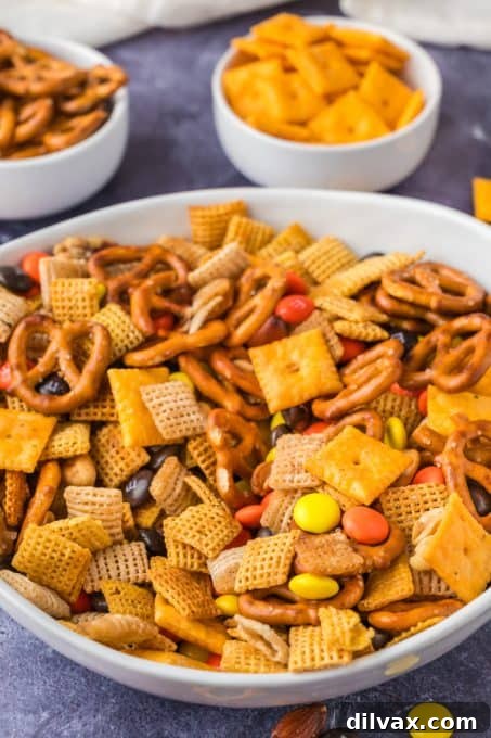 A colorful snack mix made with cereal, crackers, pretzels, and candy, perfect for sharing.