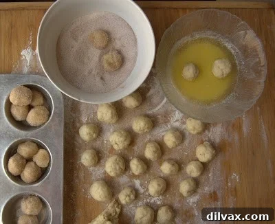 Dough balls being dipped in melted butter and rolled in cinnamon sugar mixture.