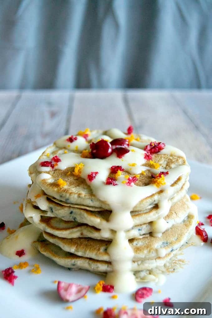 A stack of warm, golden Cranberry Pancakes, ready to be drizzled with creamy frosting.