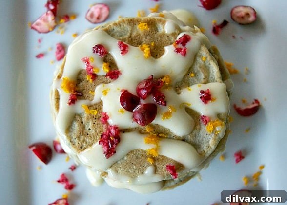 A beautifully composed shot of Cranberry Pancakes with Orange Cream Cheese Drizzle, ready to enjoy.