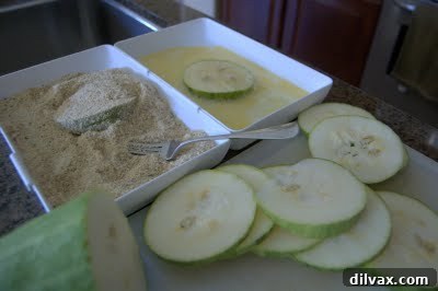 Zucchini slices being coated in a mixture of breadcrumbs and egg wash.