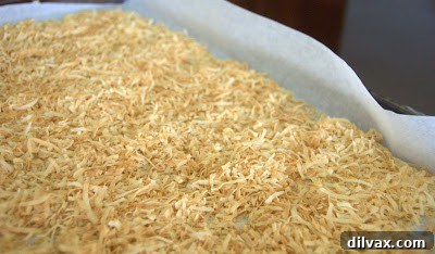 Golden brown toasted coconut spread on a parchment-lined baking sheet.