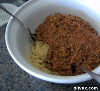 Spaghetti and meat sauce mixture in a bowl before being transferred to the pan.