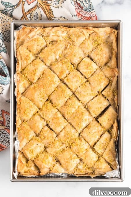 A pan of freshly baked, diamond-cut baklava squares, drizzled with syrup