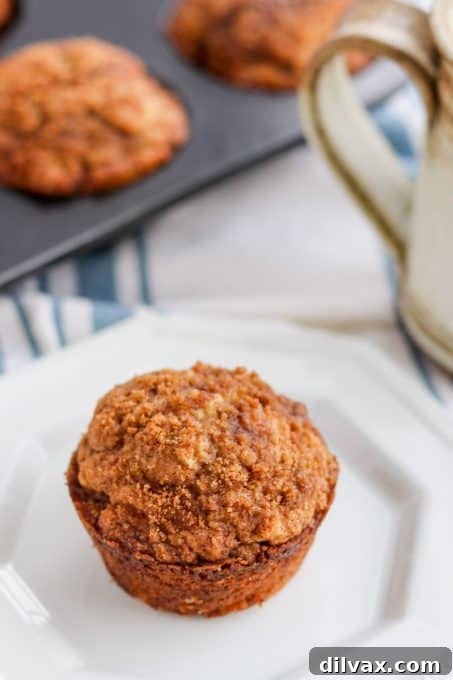 A close-up shot of a cinnamon muffin, highlighting the generous streusel topping and moist interior.