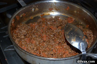 Sautéed ground beef, onion, and pepperoni simmering in a skillet with barbecue sauce and beef bouillon.
