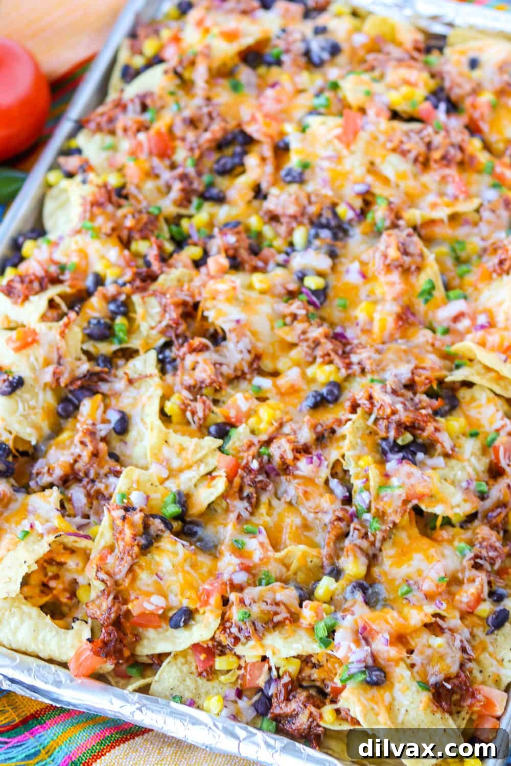 Multiple layers of delicious ingredients, including chicken, cheese, and vegetables, on tortilla chips.