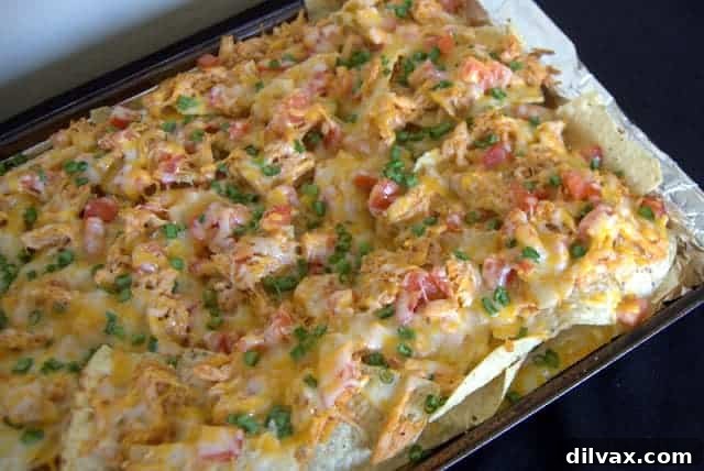 A classic image of nachos loaded with BBQ Chicken, tomatoes, green onions, and abundant melted cheese.