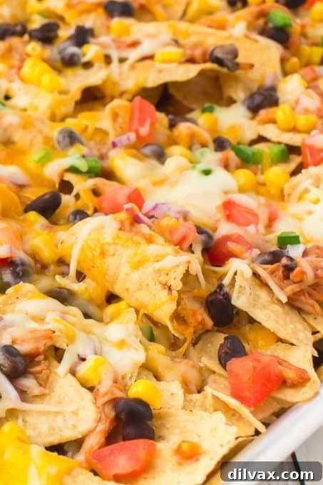 Close-up of a serving of BBQ Chicken Nachos with melted cheese and fresh toppings.