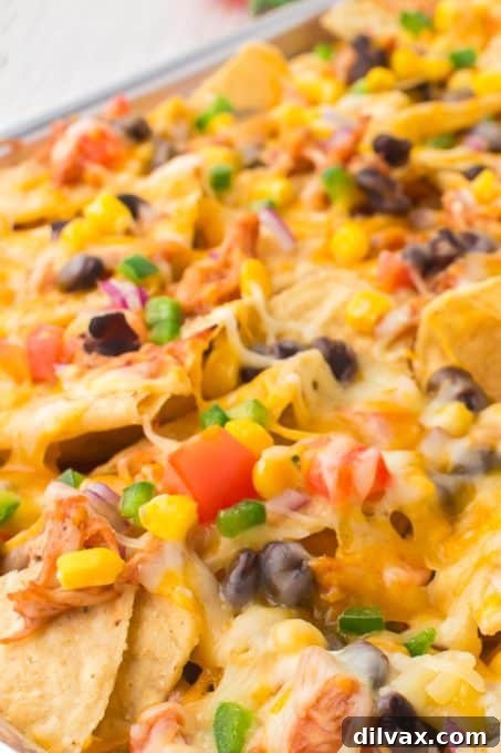 A generously loaded plate of BBQ chicken nachos, showcasing layers of chicken, cheese, and fresh toppings.