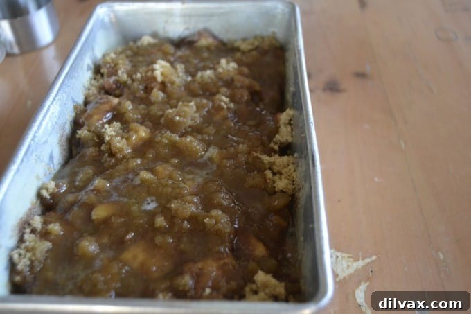 Final assembly step: drizzling melted butter over brown sugar on the unbaked Apple Cinnamon Sweet Rolls Monkey Bread
