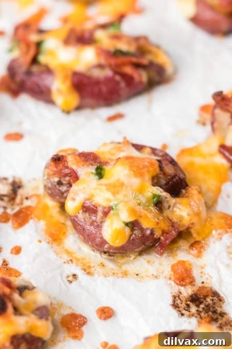 Fully Loaded Crispy Potatoes 3 Close-up shot of crispy Loaded Smashed Potatoes with melted cheese and fresh green onions, showcasing their appealing texture and toppings.