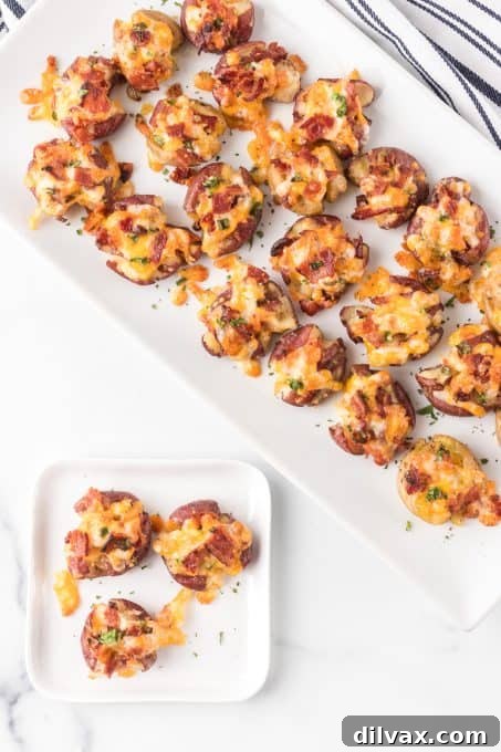 Fully Loaded Crispy Potatoes 7 A vibrant side dish of red potatoes, smashed and loaded with melted cheese, crispy bacon, and fresh green onions, ready to be served.