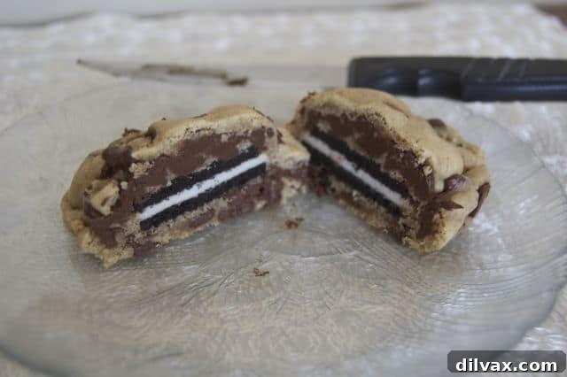 A close-up view of a half-eaten Oreo Stuffed Chocolate Chip Cookie, revealing the whole Oreo cookie perfectly embedded within the chewy chocolate chip cookie dough.