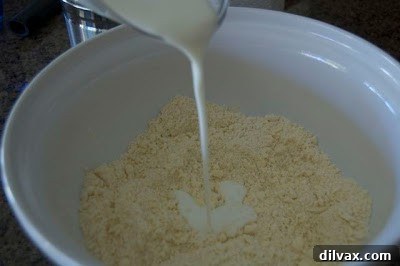Image showing the buttermilk being poured into the flour and butter mixture, beginning to form the galette dough.