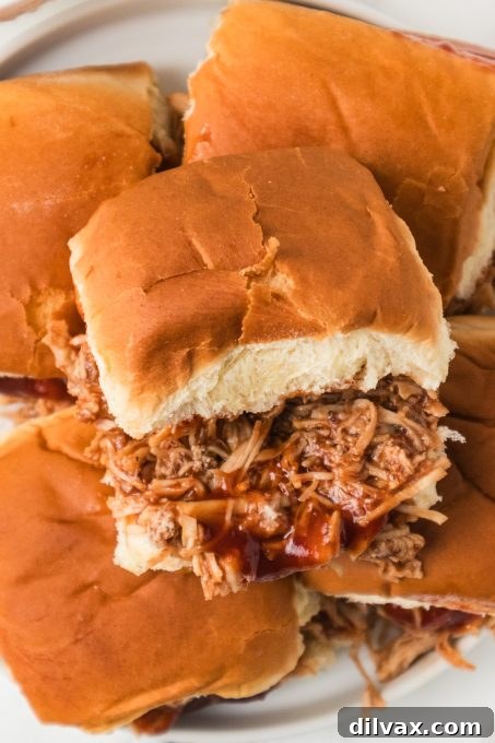 A stack of delicious shredded chicken sliders, garnished and ready to serve on a platter.