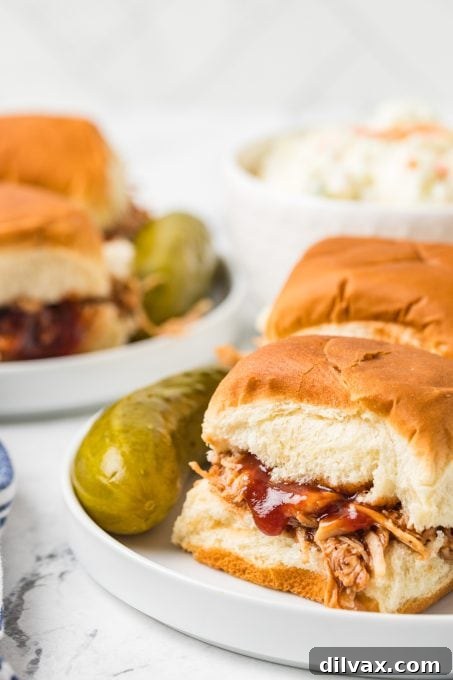 BBQ sauce drizzled generously over small chicken sandwiches on a platter.
