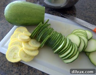 Sliced zucchini and yellow squash in a bowl with olive oil and seasoning