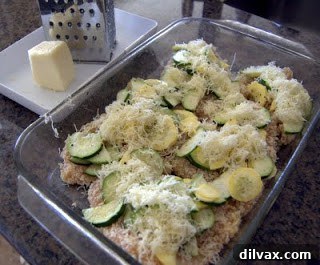 Chicken breasts topped with squash and cheese in a baking dish