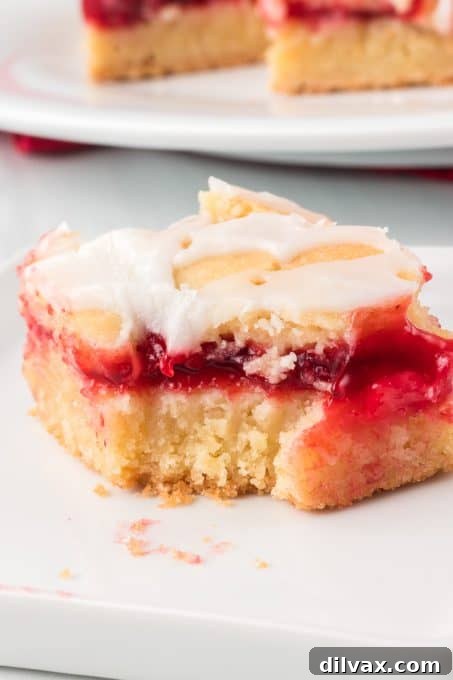 A glazed Cherry Pie Bar with a bite taken out, showing the layers.