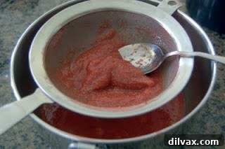 Freshly made strawberry puree in a bowl with a strainer.