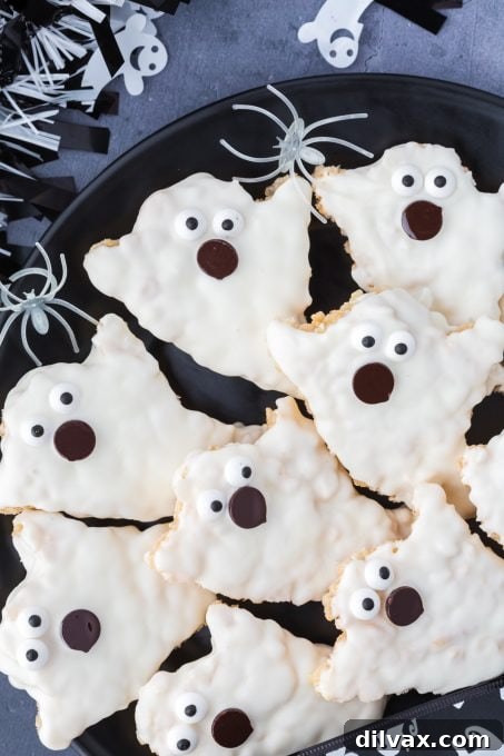 A child's hand reaching for a Halloween Ghosts Rice Krispie Treat