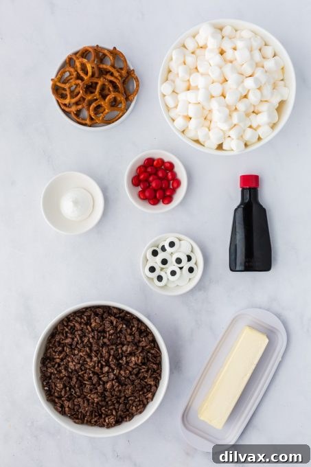 Ingredients for Reindeer Treats laid out on a table: butter, marshmallows, vanilla, cocoa krispies, icing, M&Ms, candy eyes, and pretzels.