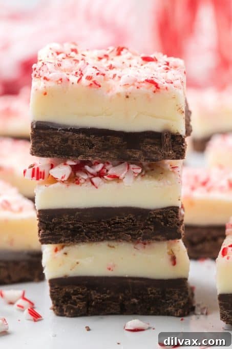 Decadent Peppermint Bark Fudge 9 Stacked squares of Peppermint Fudge, showcasing the layers.
