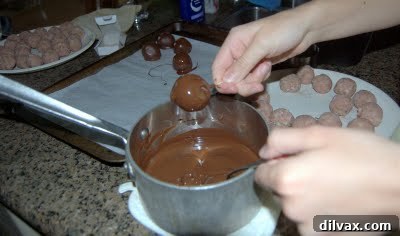 Close-up of a few chocolate-covered cake balls with a smooth, glossy finish.