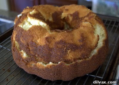 Lemon Vanilla Pound Cake on a cooling rack, being brushed with the glistening lemon syrup.