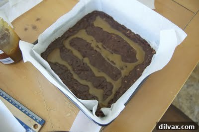 Caramel being swirled into brownie batter with a knife