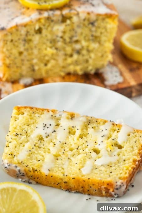 Bright Lemon Poppy Seed Loaf 8 A plated slice of glazed poppy seed bread garnished with a fresh lemon slice.