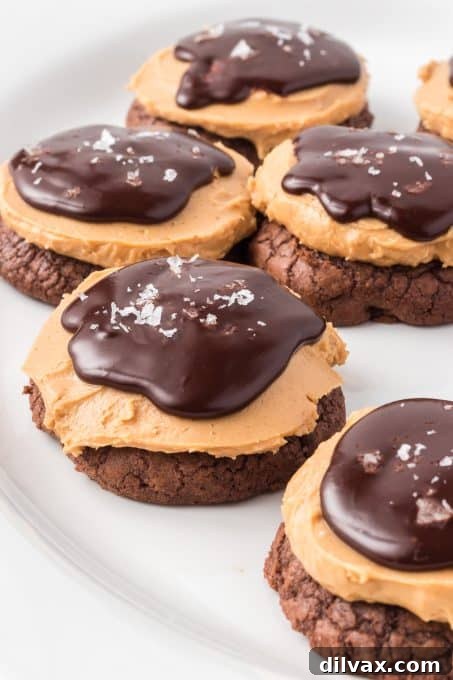 A close-up view of a Buckeye Cookie with a small bite taken, revealing the delicious layers of chocolate brownie, creamy peanut butter, and shiny ganache.
