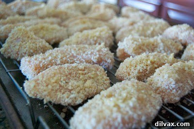 Coated chicken pieces laid out on a wire rack on a baking sheet, ready for the oven