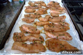 Marinated chicken strips laid out on a baking sheet