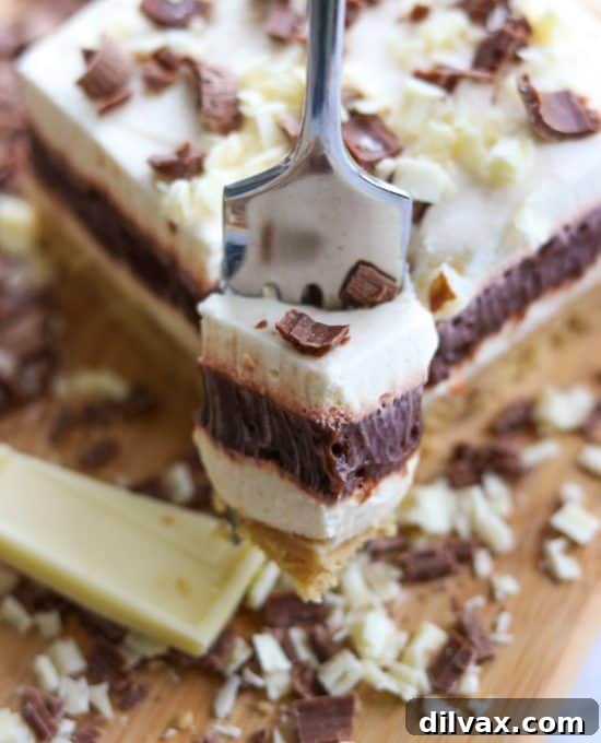 A slice of a layered no-bake dessert featuring a crumbly crust, creamy filling, and chocolate topping.