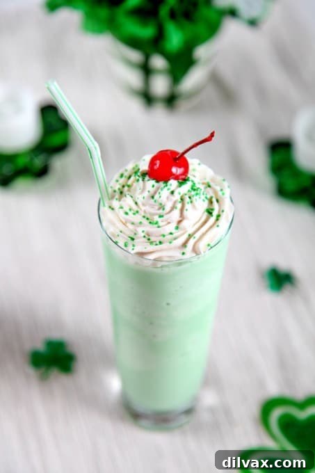 A refreshing homemade Shamrock Shake in a tall glass, topped with whipped cream and a cherry.