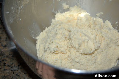 Rolling lime coconut cookie dough balls in granulated sugar before baking.