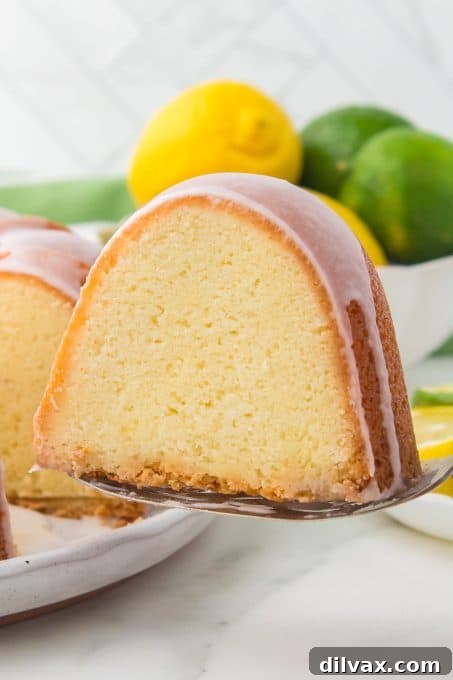 A perfectly moist slice of 7UP Cake with a crisp, sugary glazed crust, sitting on a white plate, ready to be enjoyed.