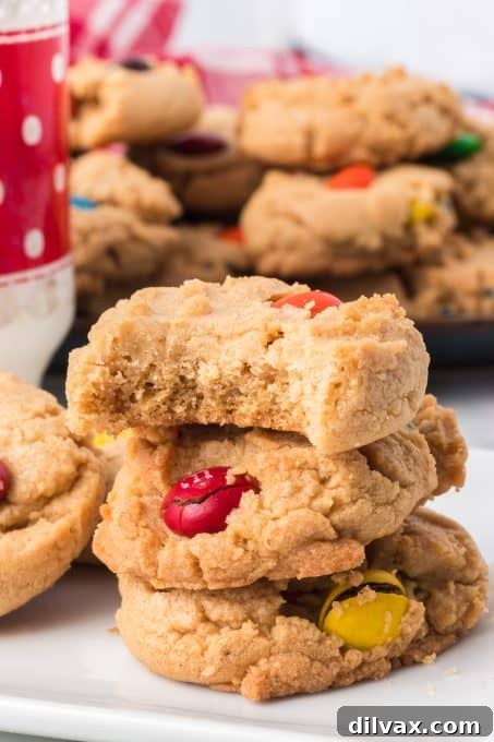 Ultimate Peanut Butter M&M Cookies 10 A bite taken out of a peanut butter cookie filled with M&M candies.