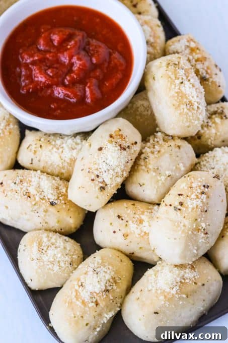 Touchdown Treats: 33 Effortless Game Day Recipes 20 Golden Parmesan Bread Bites arranged around a bowl of marinara sauce.