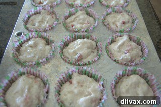 Cupcake batter scooped precisely into paper-lined muffin tins, showing proper filling level