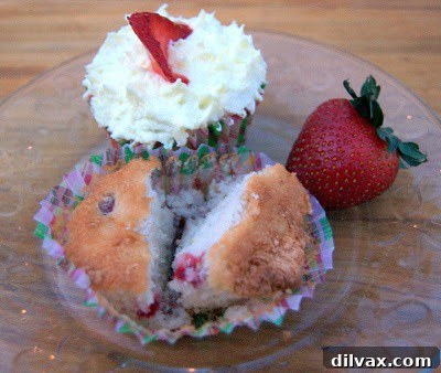 Close-up of a Strawberry Lemonade Cupcake with yellow frosting and a fresh strawberry slice on top