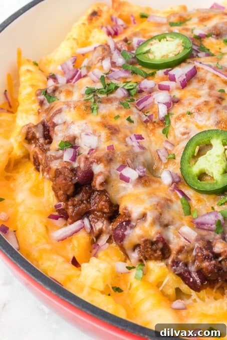 Close-up of golden French fries loaded with a rich chili and melted cheese.