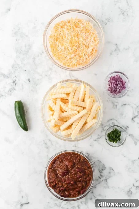 Assorted ingredients laid out for making Chili Cheese Fries, including spices, tomatoes, and ground beef.