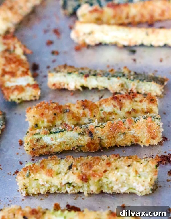 Parmesan Crusted Baked Zucchini Fries 11 Baked Parmesan Zucchini sticks arranged neatly on a baking sheet, ready for serving.